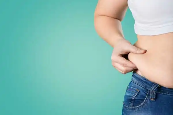 Image of woman pinching her love handles to show weight gain Twickenham